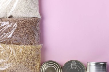 Pembe arka planda karantina süresi için yiyecek stoku. Pirinç, karabuğday, makarna, konserve yiyecek. Yemek teslimatı, Bağış, Mesaj için Yer