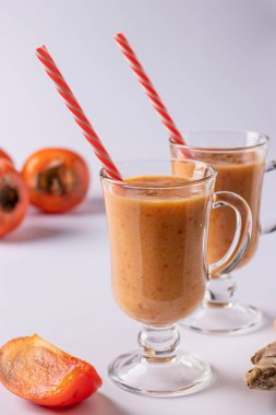 Beyaz arka planda, dikey biçimde bağışıklığı iki kadehte artırmak için hurma, elma, zencefil ve tarçın ev yapımı smoothie.