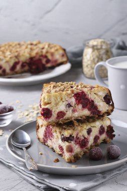 Yulaf ezmesi ve kirazlı ev yapımı süzme peynir güveci gri beton arka planda, dikey formatta.