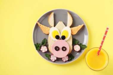 Komik bir boğa şeklinde sosisli ve yumurtalı sandviç, sarı arka planda yeni 2021 'in sembolü, çocuklar için aşçılık fikri, Top view