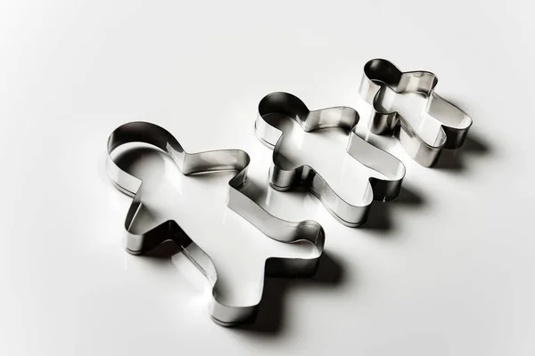 Three cookie cutters in the form of men of different sizes on a white background.