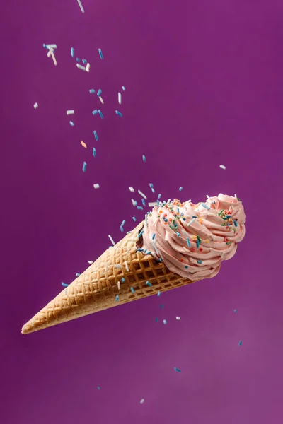 Marshmallow cake in a waffle cone. Falling cake colored with colored sugar sprinkles.