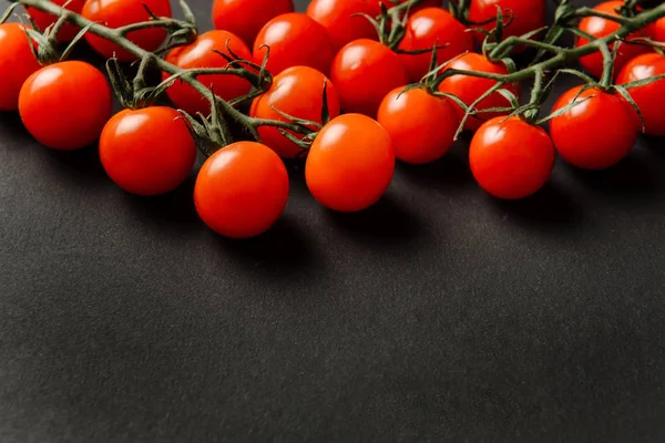 Cherry tomatoes lie on a dark textured background with space for text.