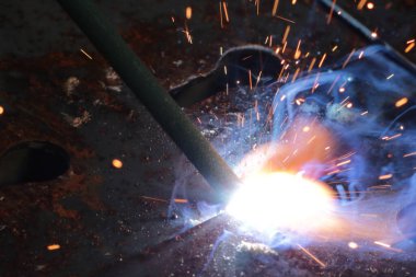 İşçi fabrikada çelikle metal kesiyor.