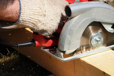 Marangoz bahçede ahşap kalaslarla çalışıyor. 