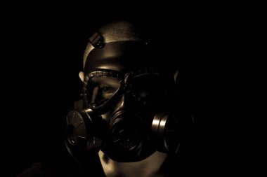Adam karanlık odada gaz maskesi takıyor.