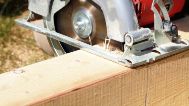 Marangoz bahçede ahşap kalaslarla çalışıyor. 