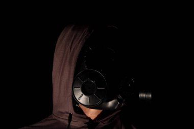 Adam karanlık odada gaz maskesi takıyor.