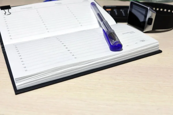Notepad for notes and office supplies on a wooden background. Daily log.