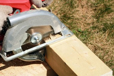 Marangoz bahçede ahşap kalaslarla çalışıyor. 