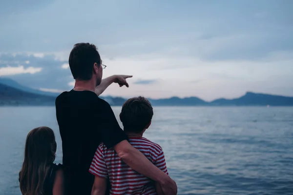 Father with son and daughter near river at sunset — Stock Photo, Image