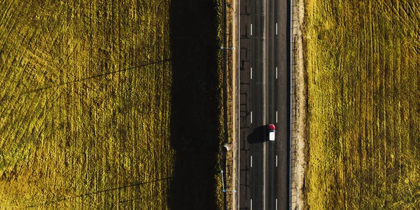 Drone vista de mover carro vermelho na estrada do lado do país — Fotografia de Stock