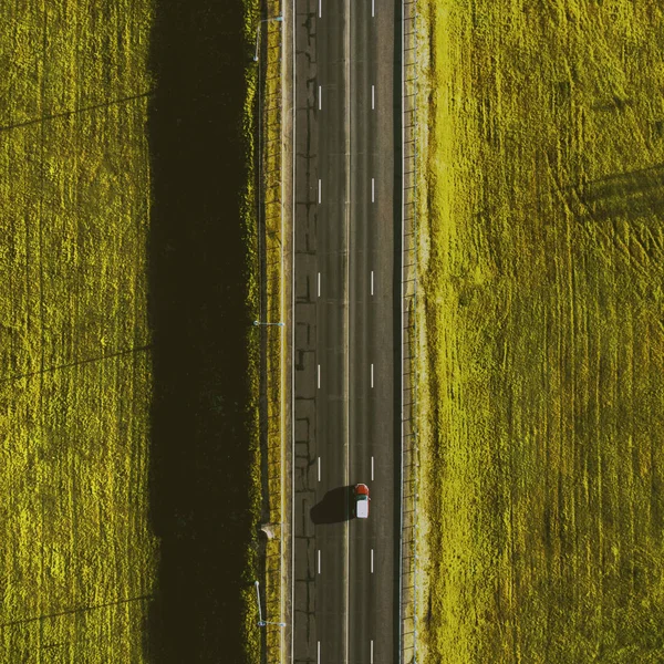 Вид с дрона на движение красной машины по проселочной дороге — стоковое фото