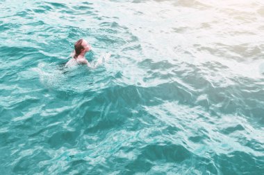 Mavi sudaki genç kadın, hava manzaralı.