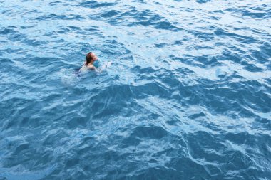 Mavi sudaki genç kadın, hava manzaralı.