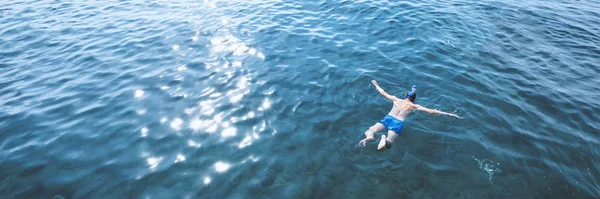 Young man in swimwear lying in blue water, aerial view — 스톡 사진