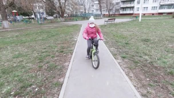 Νεαρή ξανθιά με ροζ μπουφάν και ποδήλατο. — Αρχείο Βίντεο