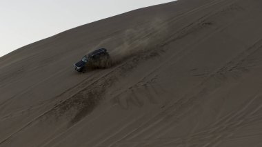 Toyota RAV4 çöl safarisinde yüksek hızda bir kum tepesinden aşağı doğru gidiyor.
