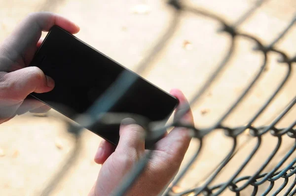 Hareket eden telefon içinde paslı çelik tel örgü çit sınırlı alan oynama