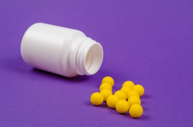 Tıp plastik şişe sarı renk hap mor bir arka plan üzerinde duruyor.