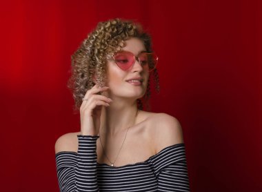 Sarı kıvırcık saçlı, pembe gözlüklü genç kız.