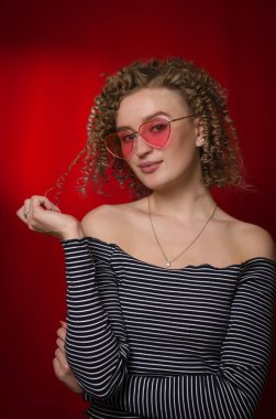 Sarı kıvırcık saçlı, pembe gözlüklü genç kız. 