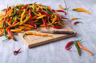 Beyaz ahşap bir masanın üzerinde sarı, kırmızı bir kesme tahtası uzanıyor.