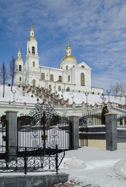 A large white Orthodox church on a mountain, against a bright bl