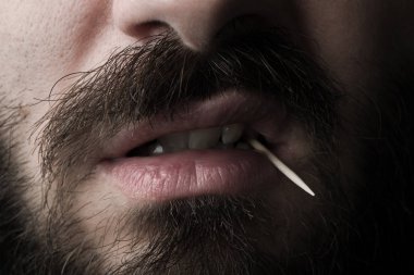 Ahşap bir kürdan ile sakallı bir adamın ağız yakın çekim