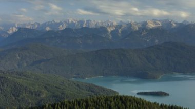 Turkuaz gölü Walchensee 'nin güneşli bir günde Sassau adasıyla dağlarda süratli olması, bulutların Bavyera Alpleri ve ormanı üzerinde hareket etmesi, Jochberg' in zirvesinden yazın Bavyera 'ya ulaşması,