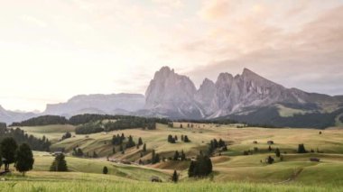 Dolomite Alplerinde Seiser Alm 'de sabah vaktinin dolması ilkbaharda güneş ışınları, gökyüzünde hareket eden bulutlar ağaçlar ve ön planda kulübeleri olan tarlalar, Güney Tyrol İtalya