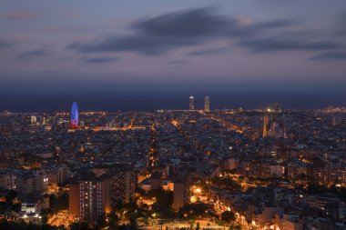 Gece Barselona 'da Sagrada Familia Katedrali ve Torre Agbar Kulesi ile aydınlanan gökyüzü Bunkers del Carme' ın sokak lambaları