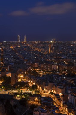 Gece Barselona 'da Sagrada Familia Katedrali ve Torre Agbar Kulesi ile aydınlanan gökyüzü Bunkers del Carme' ın sokak lambaları