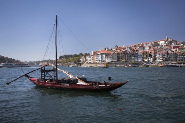 Porto şehrinin önündeki tarihi şarap teknesi güneşli bir günde Douro nehri, nehir kenarında evler...