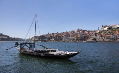 Porto şehrinin önündeki tarihi şarap teknesi güneşli bir günde Douro nehri, nehir kenarında evler...