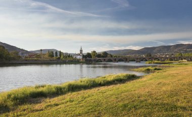 Köprü Ponte de Lima Kilisesi, güneşli bir günde öğleden sonra, nehir kenarında Lima Nehri ve nehir kenarında yeşil çimenler.