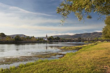 Köprü Ponte de Lima Kilisesi, güneşli bir günde öğleden sonra, nehir kenarında Lima Nehri ve nehir kenarında yeşil çimenler.
