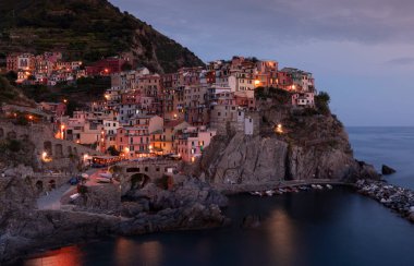 Cinque Terre 'deki Manarola köyünün renkli evlerinin olduğu körfez, gece boyunca sokak ışıkları, uçurumlardaki kasaba, İtalya