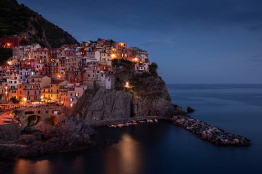 Cinque Terre 'deki Manarola köyünün renkli evlerinin olduğu körfez, gece boyunca sokak ışıkları, uçurumlardaki kasaba, İtalya