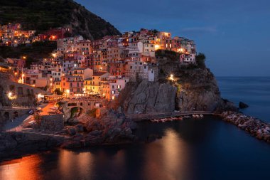 Cinque Terre 'deki Manarola köyünün renkli evlerinin olduğu körfez, gece boyunca sokak ışıkları, uçurumlardaki kasaba, İtalya