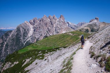 Sırt çantalı bir adam yaz aylarında Three Peaks etrafında yürüyüş yapıyor, arka planda dağlar, mavi gökyüzü, Güney Tyrol İtalya