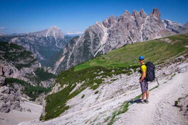 Sırt çantalı bir adam yaz aylarında Three Peaks etrafında yürüyüş yapıyor, arka planda dağlar, mavi gökyüzü, Güney Tyrol İtalya
