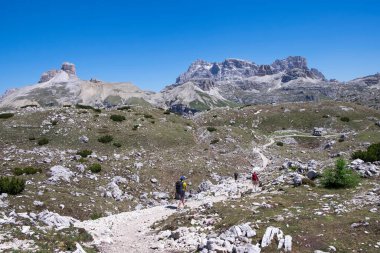 Sırt çantalı insanlar yaz aylarında Three Peaks 'in etrafında yürüyüş yapıyorlar, arka planda dağlar, mavi gökyüzü, Güney Tyrol İtalya