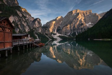 Dolomite Alpleri 'nde günbatımında Prag Gölü' nde tekneli kayıkhane, Güney Tyrol İtalya 'da su yüzeyindeki dağların yeniden çekilmesi.