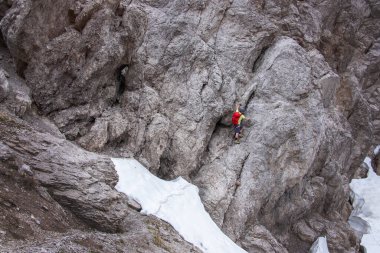 Kırmızı sırt çantalı bir adam Wankspitze 'de kayaya tırmanıyor. Kar tarlası, Mieminger sıradağları, Tyrol...