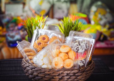 Tanımlama bilgileri ve rengarenk, renkli arka plan üzerinde bir hasır ahşap sepeti hamur işleri ile plastik tek kullanımlık kaplar