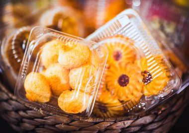 Tanımlama bilgileri ve rengarenk, renkli arka plan üzerinde bir hasır ahşap sepeti hamur işleri ile plastik tek kullanımlık kaplar