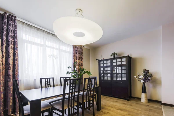 The interior dining area with a table, a chandelier and a large chest of drawers — Stock Photo, Image