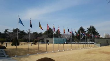 Ulusal bayrakları sallayarak BM mezarlığı Busan, Güney Kore, Asya havadaki / ülke bayrakları sallayarak BM mezarlığı Busan, Güney Kore, Asya Şubat-22-2018 zaman havada. BM Memorial mezarlığı Kore BM askerleri 16 ülkeden onur 