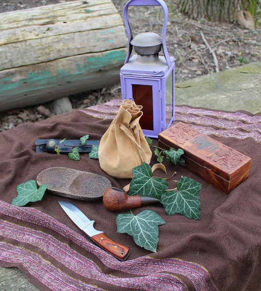 Natürmort - vintage bir lamba, bıçak, ahşap boru, kutusu ve bir bahçe tabloda sarmaşık yaprakları ile düzenlenmiş bir poach